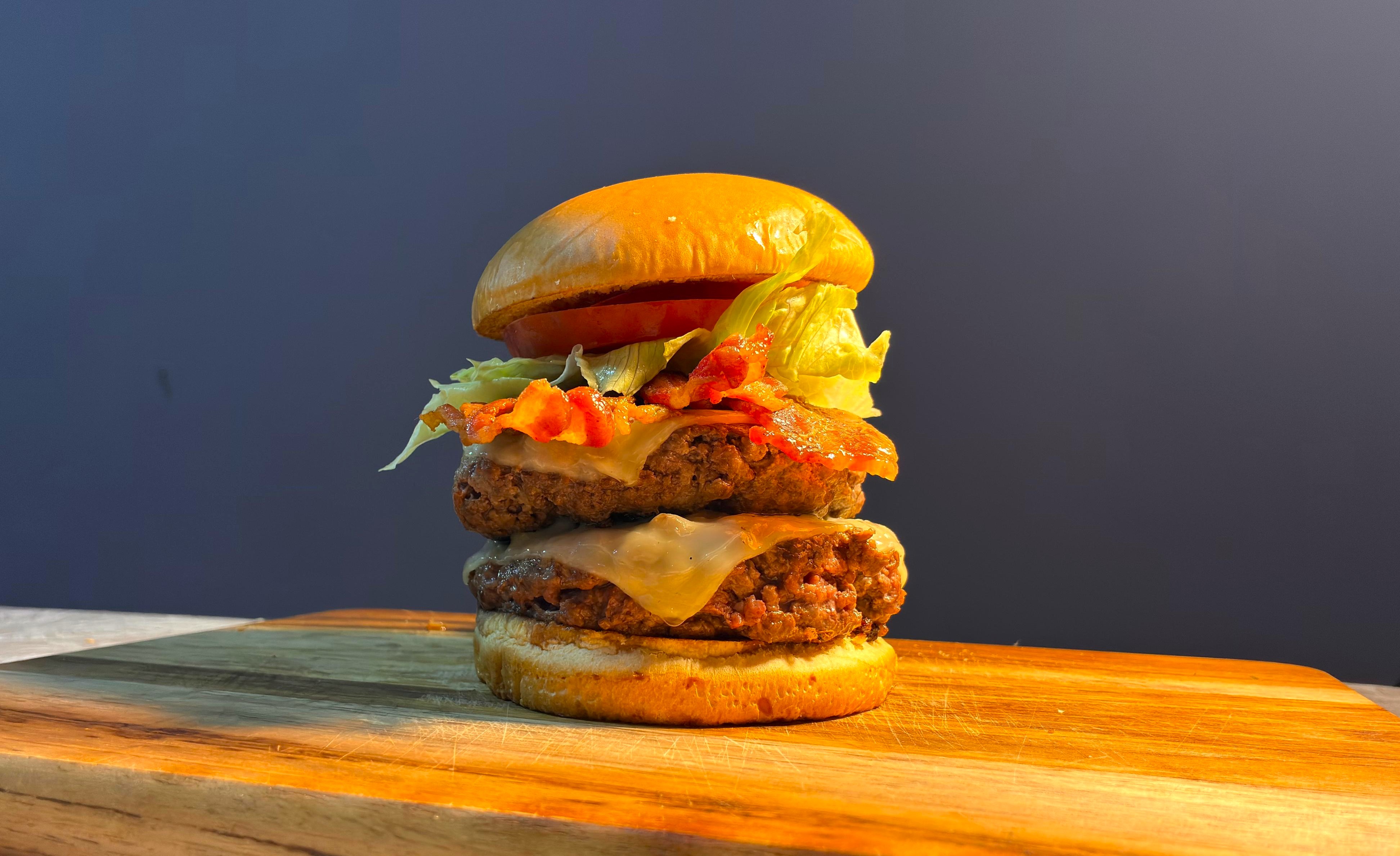 Hambúrguer duplo suculento com queijo derretido, bacon e cebola caramelizada